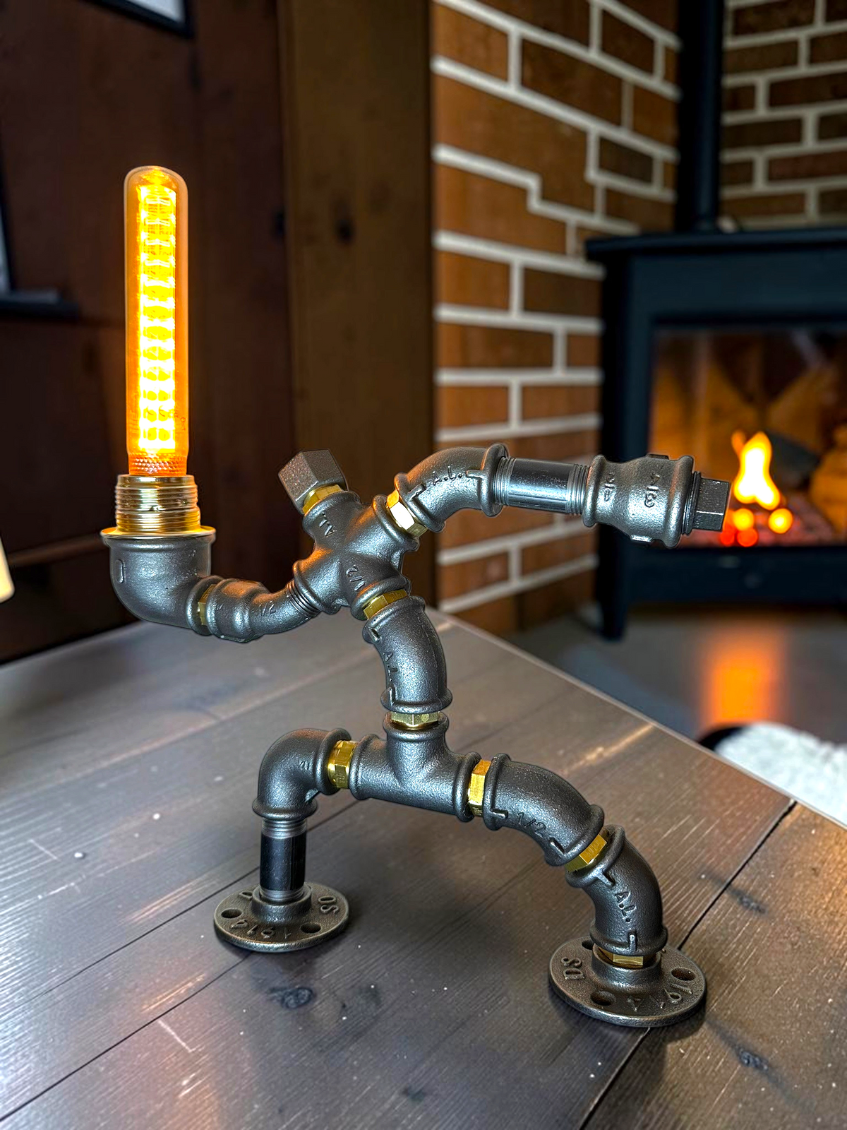 IronPunky Hampelmann Tischleuchte aus dunklen Industrierohren mit leuchtender Edison-Glühbirne im Wohnzimmer