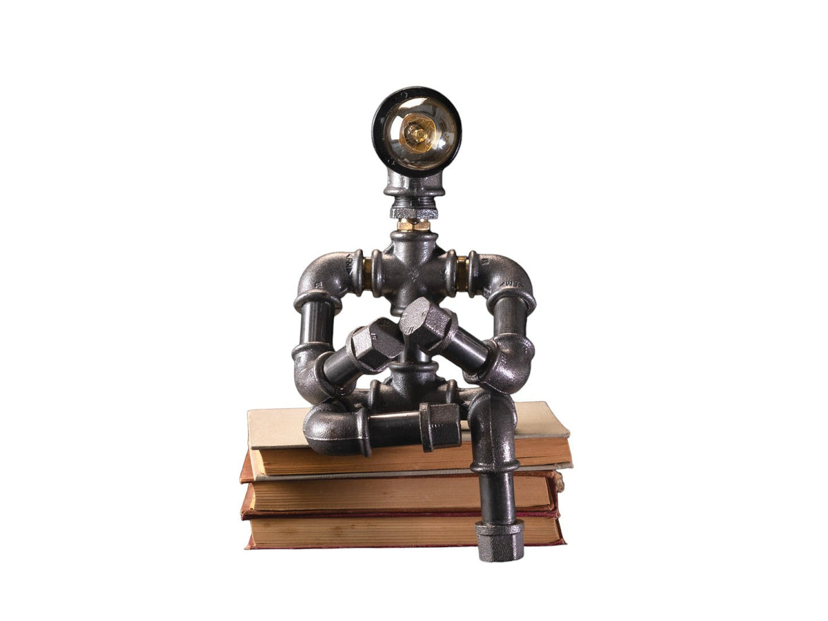 IronPunky Kapitelträumer Tischlampe aus schwarzem Temperguss in Form einer lesenden Figur auf alten Büchern